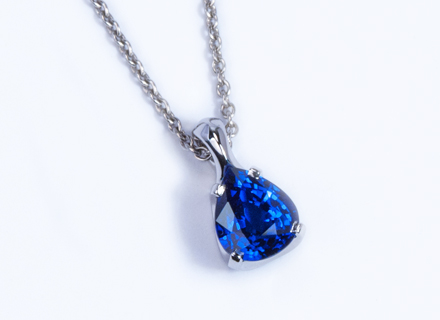 Fourclaw platinum pendant with a pear cut blue sapphire