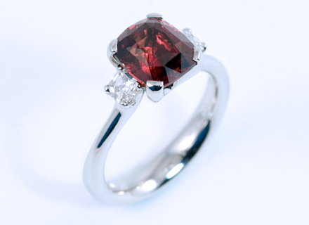 Four claw three stone platinum ring with a cushion cut red sapphire and asscher cut diamonds